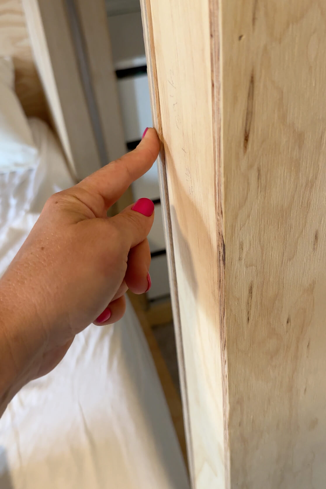 Using a router to clean up the uneven edges of plywood on a bunk bed frame.